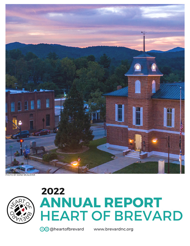 Photo of downtown Brevard at sunset with blue and red hues in the sky behind the mountains in the background.